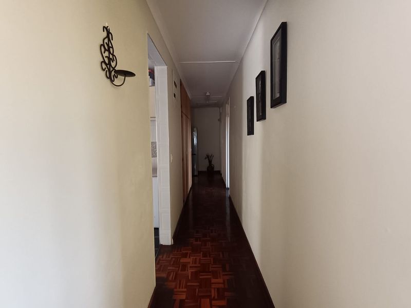 A functional hallway featuring classic parquet flooring and built-in storage cupboards, providing access to adjacent rooms within the home.