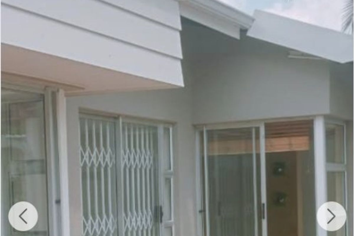 Rear exterior view of the house featuring a brick paved patio area with sliding glass doors and security gates.