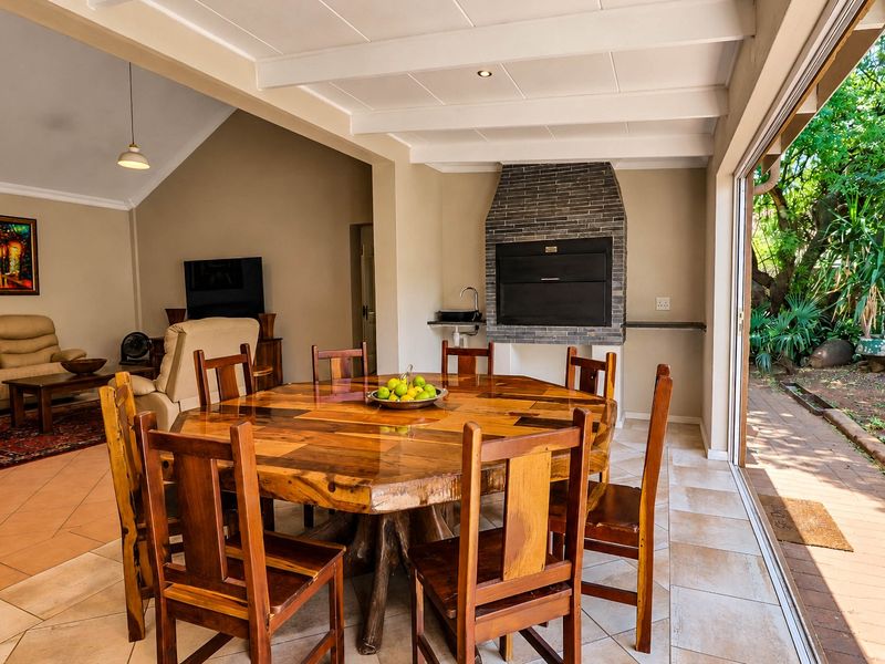 Spacious open-plan living and dining area featuring a built-in braai, tiled floors, and large sliding doors opening to the garden.