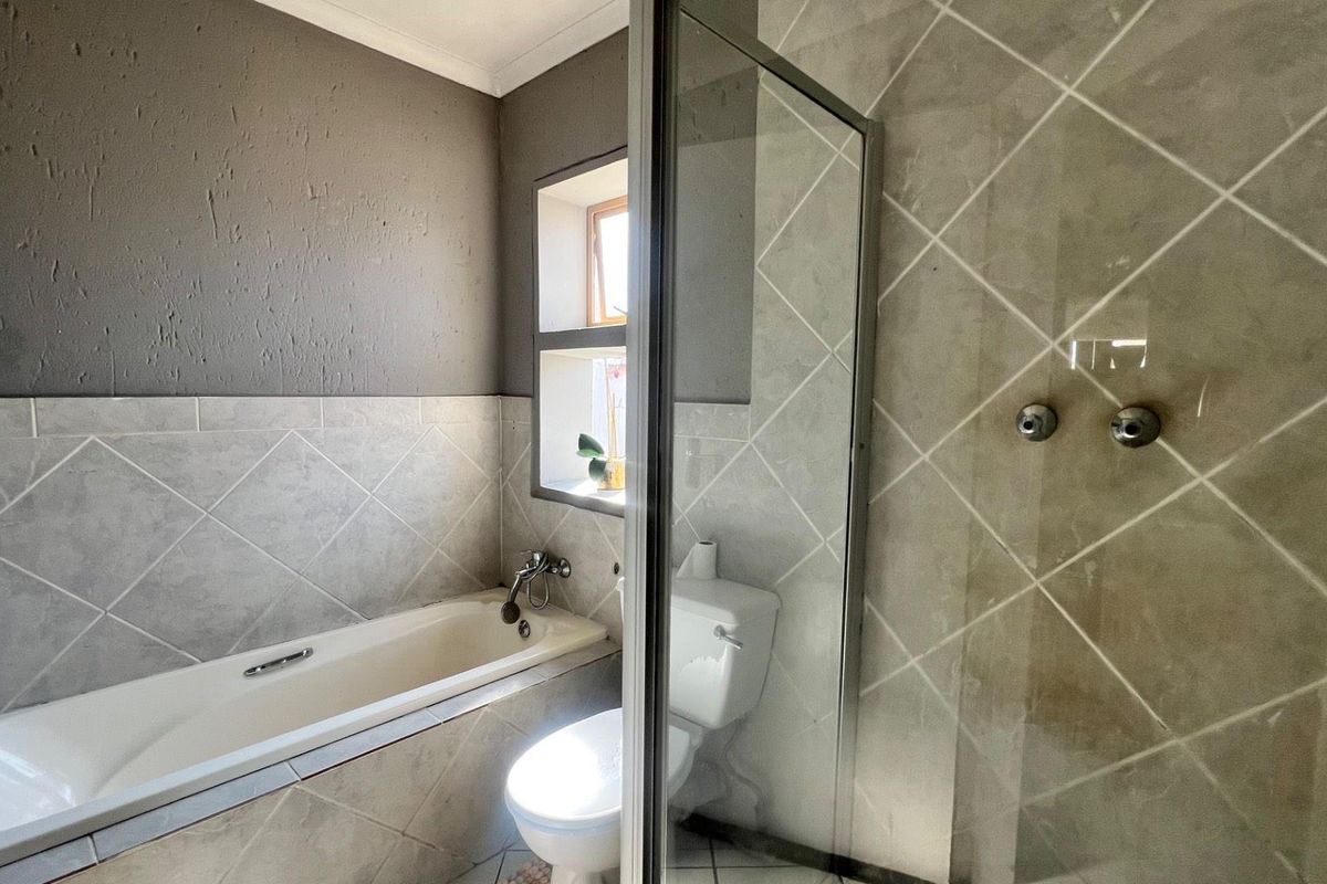 A functional bathroom featuring a built-in bathtub, a separate glass-enclosed shower, and tiled wall finishes.