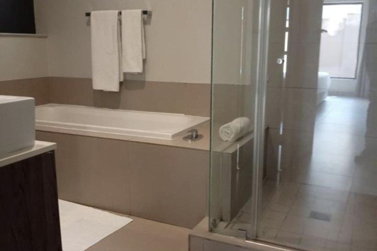 Modern bathroom featuring a built-in bathtub, a separate glass-enclosed shower, and a vanity unit with a basin, finished with neutral floor tiles.