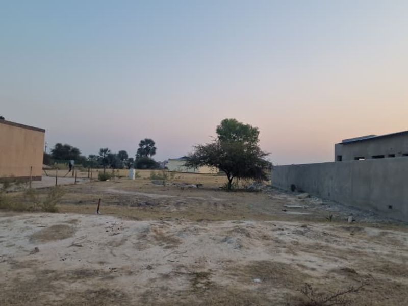 A view of the rear yard area featuring a boundary wall and open, undeveloped land.