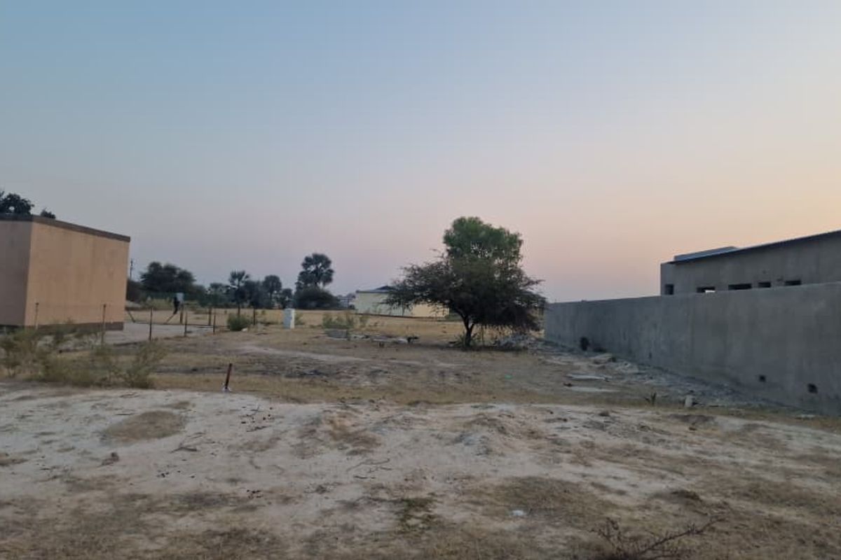A view of the rear yard area featuring a boundary wall and open, undeveloped land.