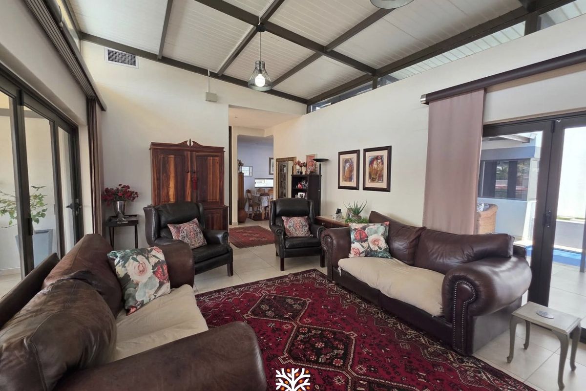 Spacious living room featuring an exposed beam ceiling, tiled flooring, and large sliding glass doors that provide ample natural light and access to the outdoors.