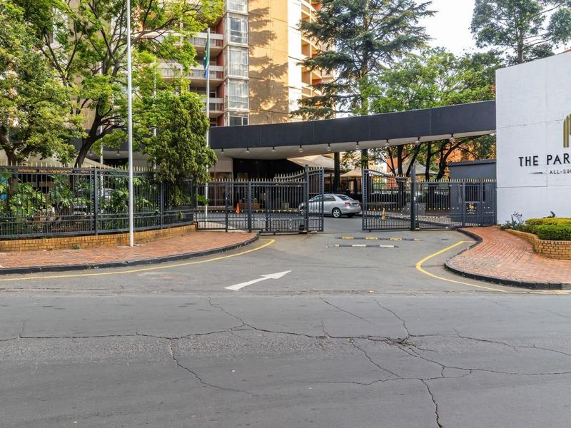 The main entrance to The Parktonian, featuring a secure gated driveway, perimeter fencing, and clear building signage.