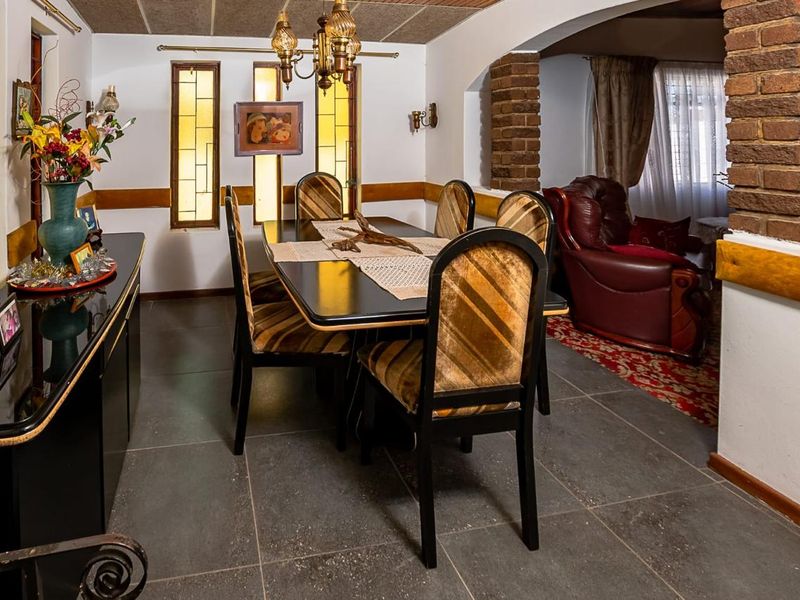 Dining area featuring tiled floors, exposed brick pillars, and an arched transition to the adjacent living space, showcasing a traditional layout.