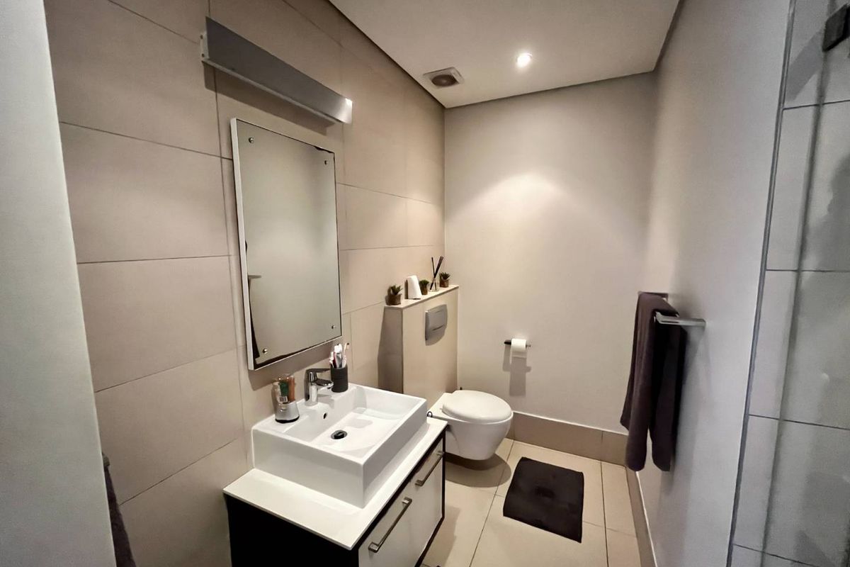 Modern bathroom featuring a wall-mounted toilet, a contemporary vessel sink vanity, and neutral large-format wall tiles.