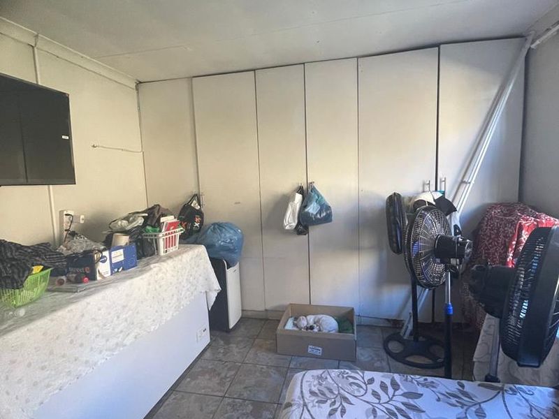 A bedroom featuring built-in cupboards and tiled flooring, currently used as a multi-purpose living space.