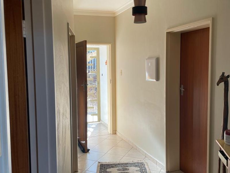 A clean and functional hallway featuring tiled flooring, neutral wall tones, and multiple internal wooden doors providing access to adjacent rooms.