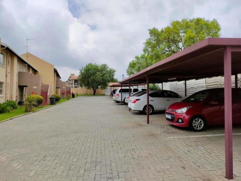 Outdoor parking area featuring covered carports and paved driveway within the apartment complex grounds.