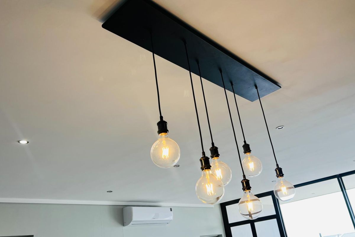 A modern interior space featuring a contemporary multi-pendant light fixture and a wall-mounted air conditioning unit.