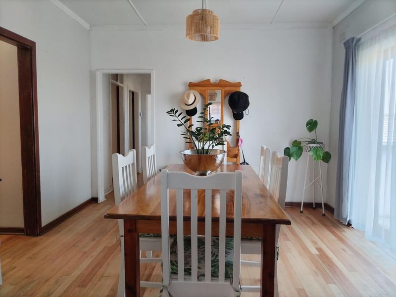 A bright dining room featuring polished hardwood flooring and a central ceiling light fixture, providing a clean and functional space for meals.
