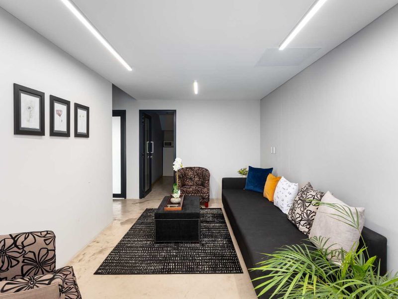 Modern living area featuring polished concrete flooring and sleek recessed linear lighting, creating a clean and contemporary professional space.