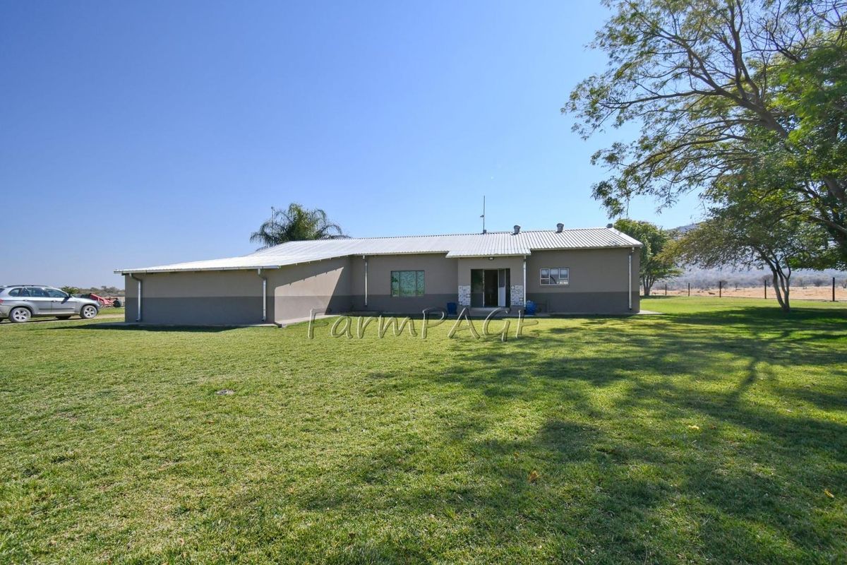 A view of the rear exterior of the small holding, featuring a single-story structure with a metal roof and surrounding lawn.