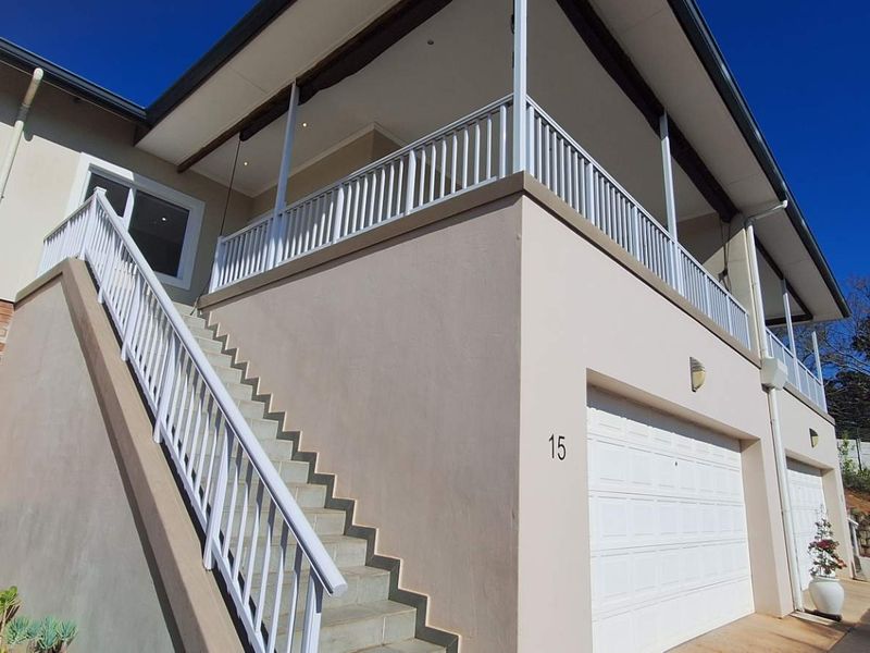 Front elevation of a townhouse featuring a double garage, external staircase leading to an upper-level balcony, and well-maintained exterior finishes.