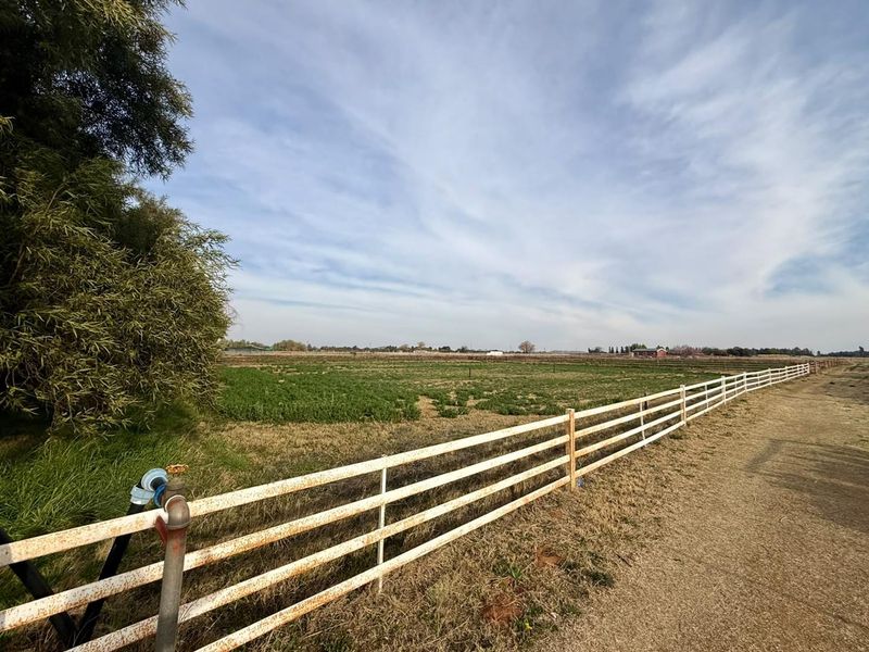 Expansive farm land view featuring post and rail fencing and a functional water standpipe on the property perimeter.