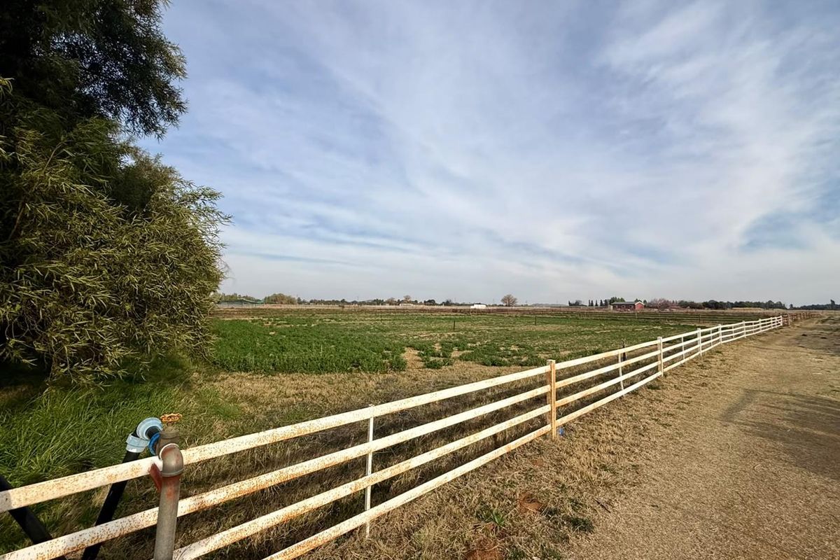 Expansive farm land view featuring post and rail fencing and a functional water standpipe on the property perimeter.