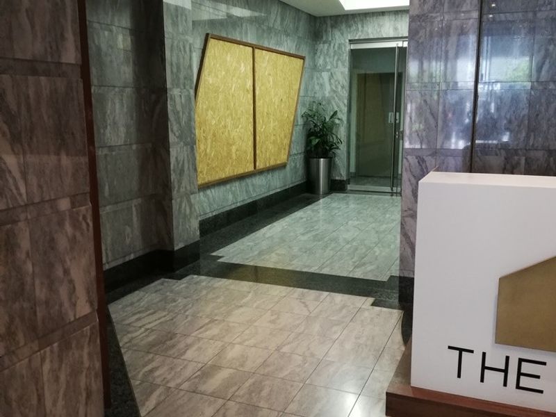 Professional office building entrance lobby featuring marble wall cladding, polished marble flooring, and a built-in reception desk.