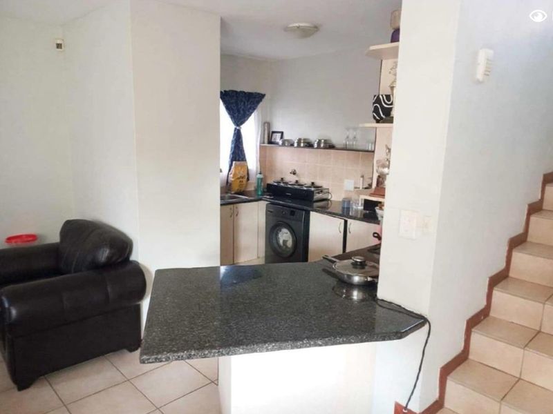 Open plan kitchen featuring granite countertops and built-in cabinetry, seamlessly connected to the living area and adjacent staircase.