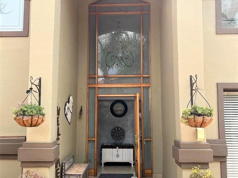 A grand, double-height entrance featuring tiled flooring, decorative pillars, and a large transom window, creating an inviting and well-maintained facade.