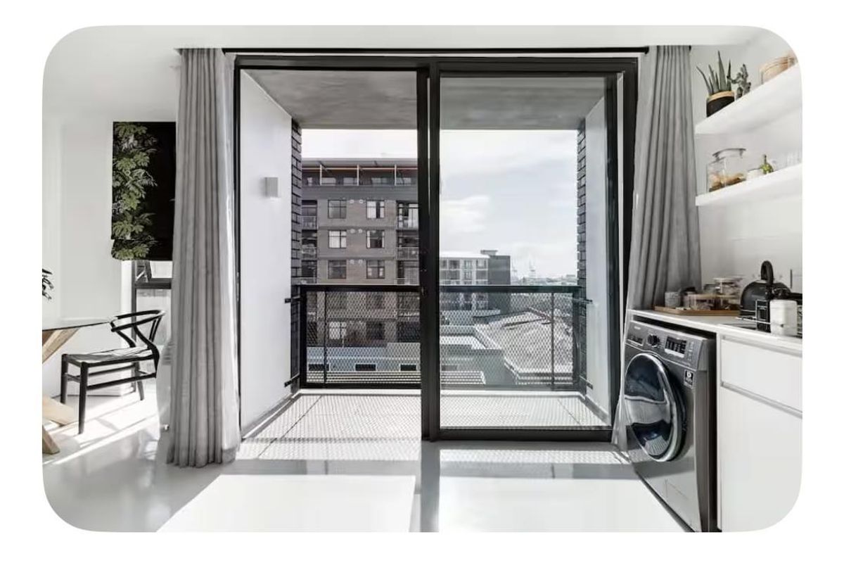Modern open-plan living area featuring polished concrete floors, built-in shelving, and a seamless transition to a private balcony with urban views.