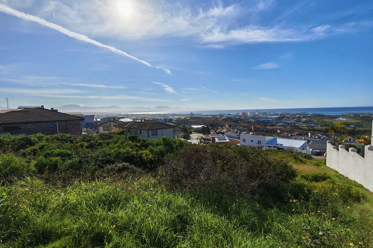 A scenic elevated view overlooking a residential neighbourhood with coastal and mountain vistas in the distance.