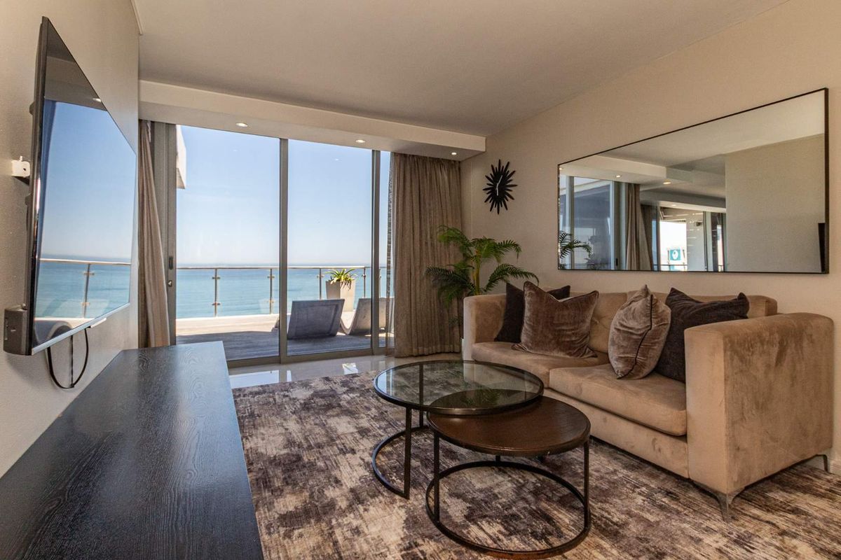Modern living room featuring large sliding glass doors leading to a balcony with expansive ocean views and recessed ceiling lighting.