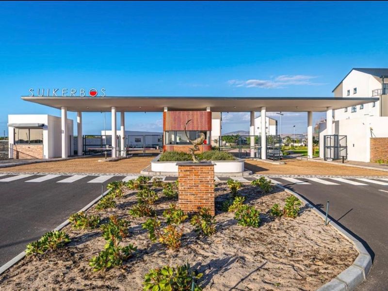 Modern secure entrance gatehouse for Suikerbos estate featuring a paved driveway, boom gates, and landscaped garden beds.