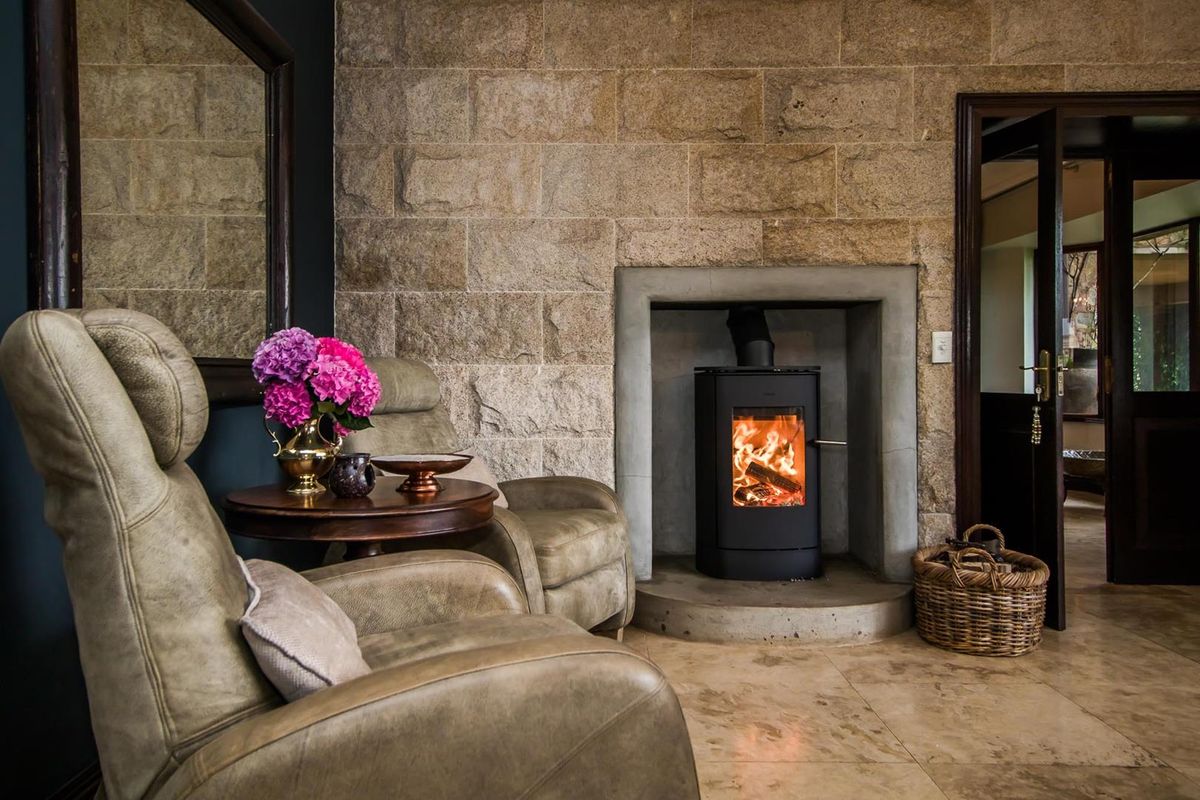 A cozy living room featuring a prominent natural stone feature wall and a modern built-in wood-burning fireplace with a concrete hearth.