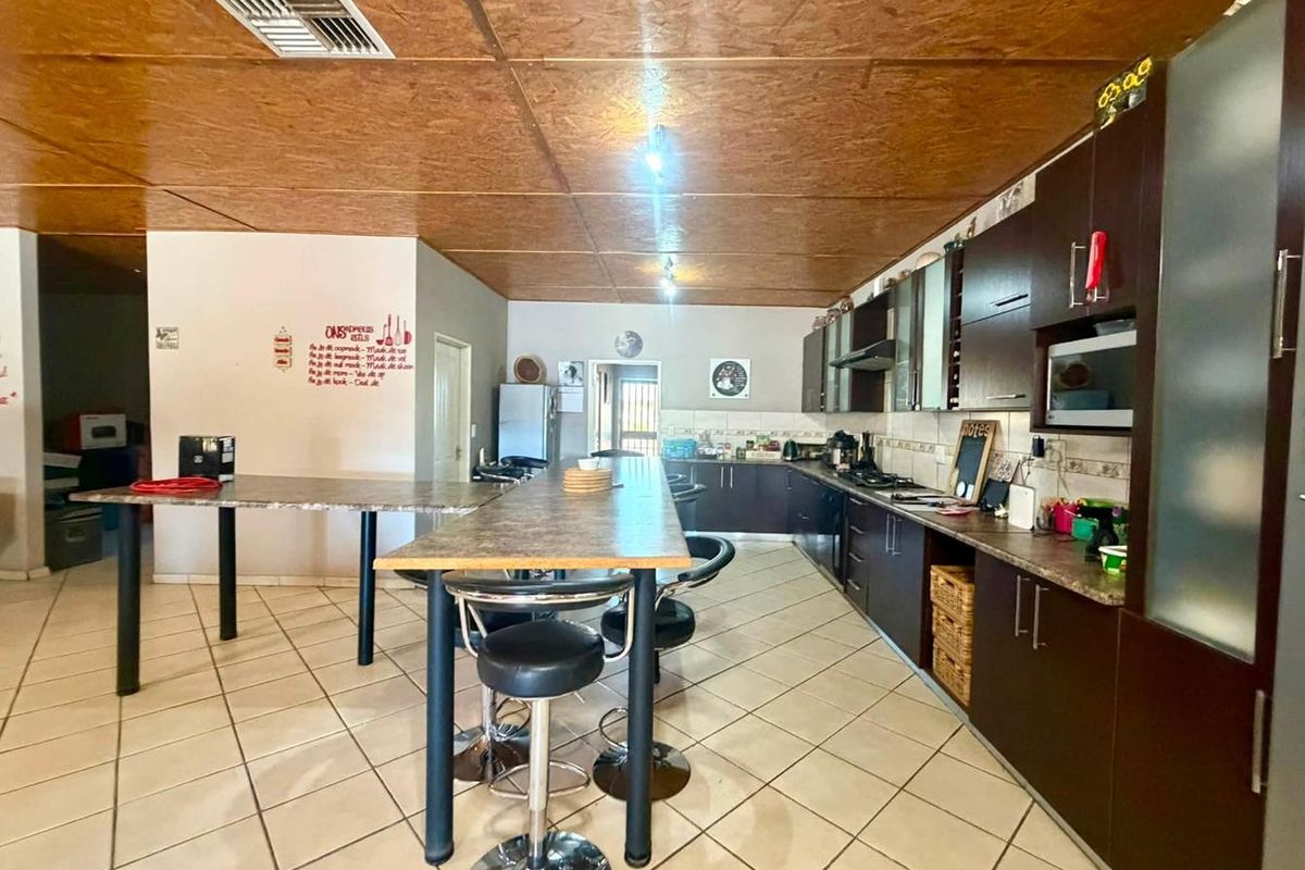 Spacious kitchen featuring dark built-in cabinetry, laminate countertops, a breakfast bar, and tiled flooring with recessed ceiling lighting.