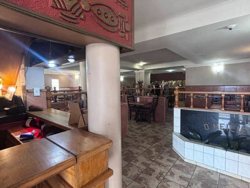 Interior view of a bar area featuring a built-in counter, decorative wall detailing, tiled flooring, and timber balustrades within a commercial space.
