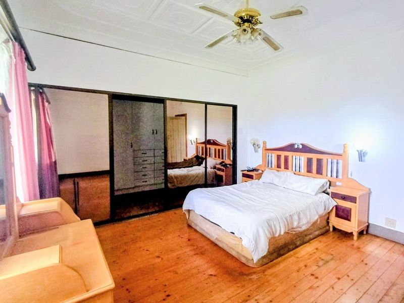 Spacious bedroom featuring original pressed metal ceilings, timber flooring, and large built-in mirrored wardrobes providing ample storage space.