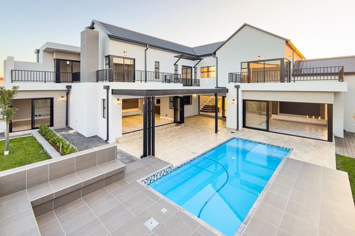 Modern double-story residence featuring a spacious patio, swimming pool, and seamless indoor-outdoor flow through large sliding glass doors.