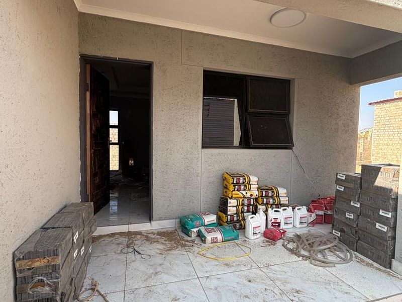 Front entrance porch area featuring tiled flooring and textured wall finishes, currently in a state of construction or final finishing.