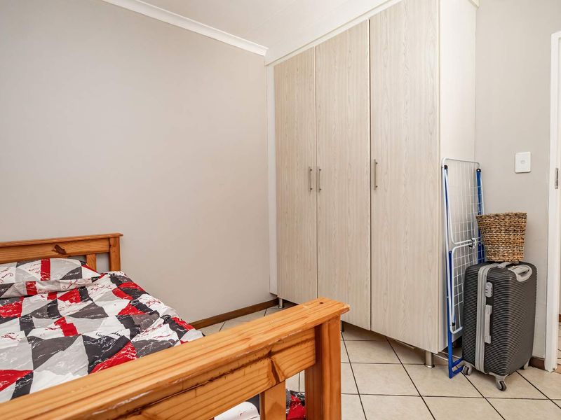 A bedroom featuring tiled flooring and a built-in wardrobe with light wood-grain finish.
