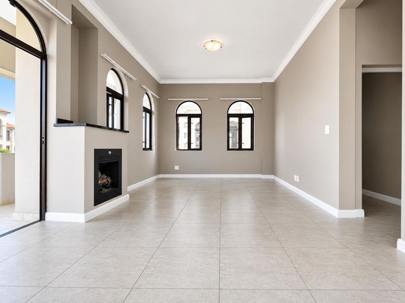 Spacious living area featuring neutral tiled flooring, elegant arched windows, and a built-in fireplace, offering a bright and versatile space for relaxation.