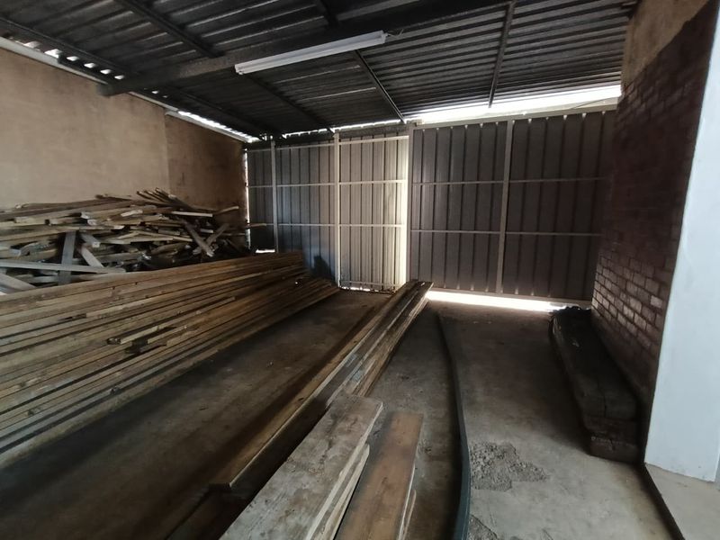 A spacious industrial garage or storage area featuring concrete flooring, exposed brickwork, and large metal sliding doors.