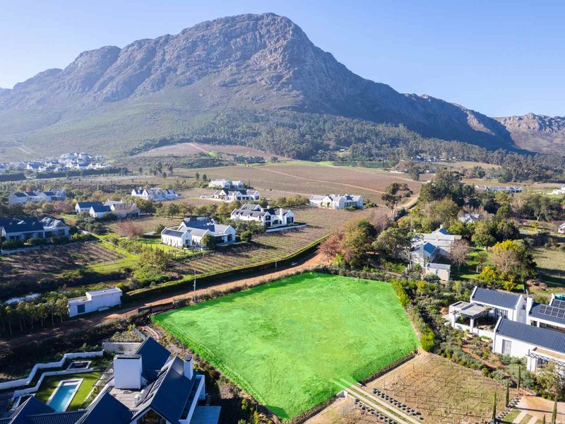 An aerial view of a vacant residential plot situated in a scenic estate with mountain views.