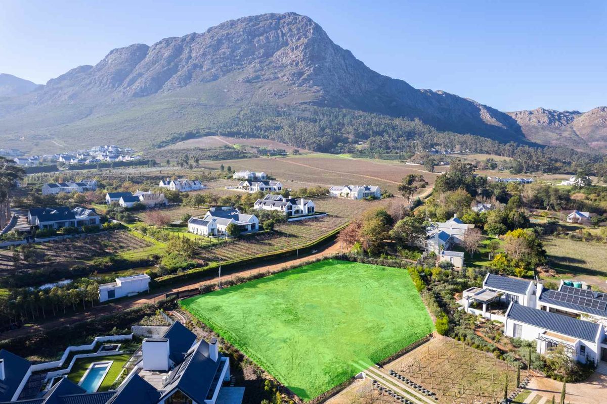 An aerial view of a vacant residential plot situated in a scenic estate with mountain views.