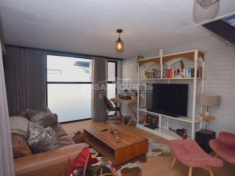 A bright living room featuring a painted brick feature wall, laminate flooring, and large sliding glass doors providing natural light.