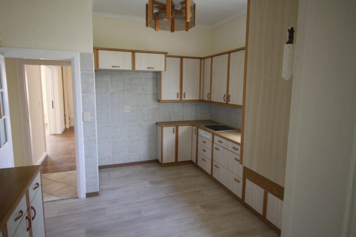 A functional kitchen featuring light-toned cabinetry, a built-in hob, tiled splashbacks, and durable flooring, offering a clean and practical workspace.