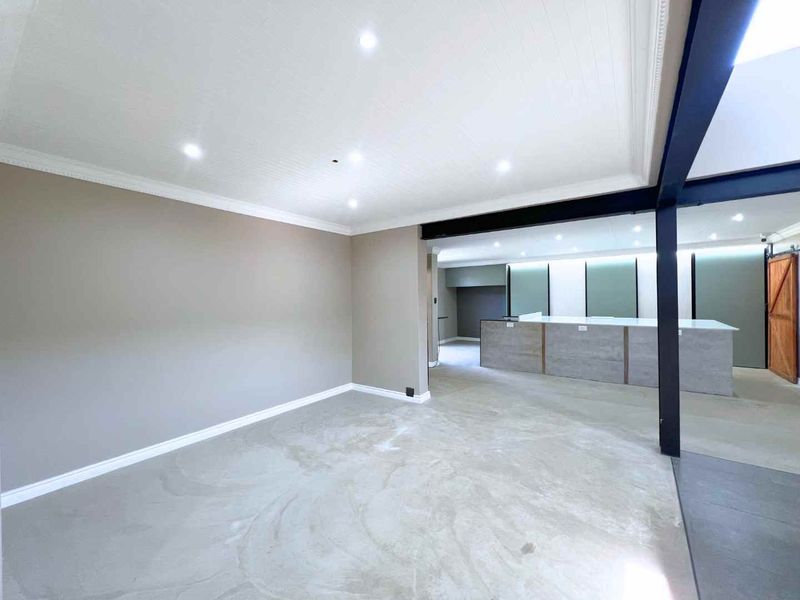 Spacious open-plan living area featuring polished concrete floors, recessed lighting, and a modern kitchen island with a sleek, contemporary finish.