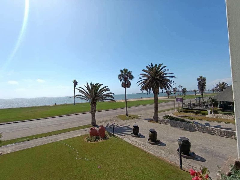 Elevated view overlooking a coastal road, landscaped garden, and the ocean beyond.