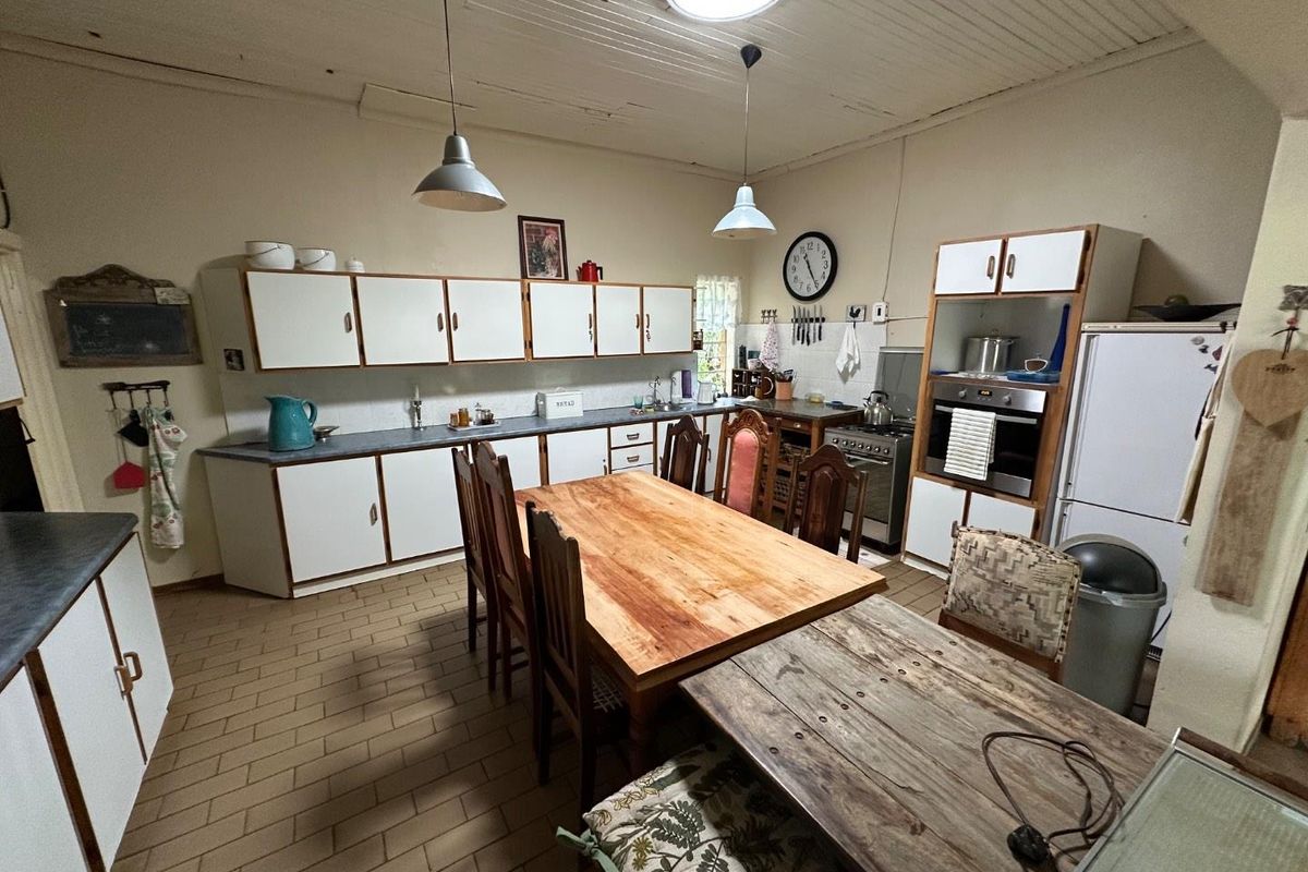 A spacious kitchen featuring built-in cabinetry, laminate countertops, a built-in oven, and tiled flooring, offering a functional layout with potential for modernization.
