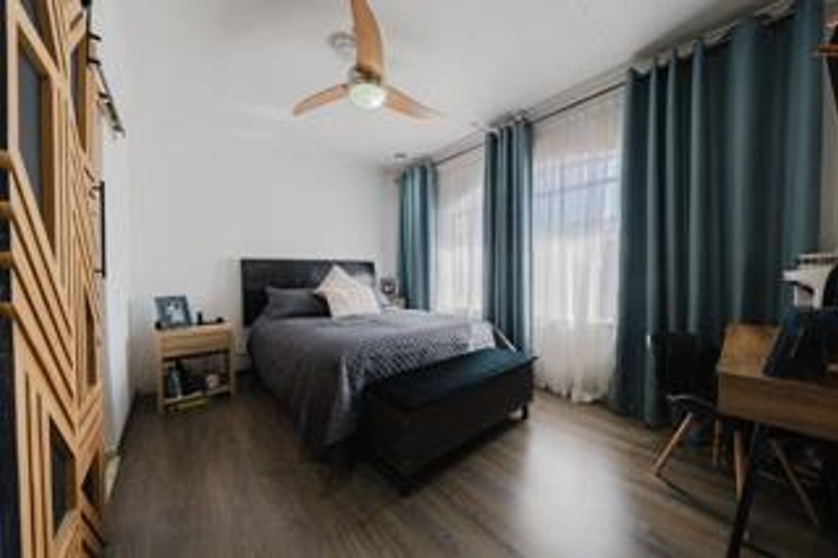 A well-maintained bedroom featuring laminate flooring, a ceiling fan, and a decorative sliding barn door, offering a comfortable and functional living space.
