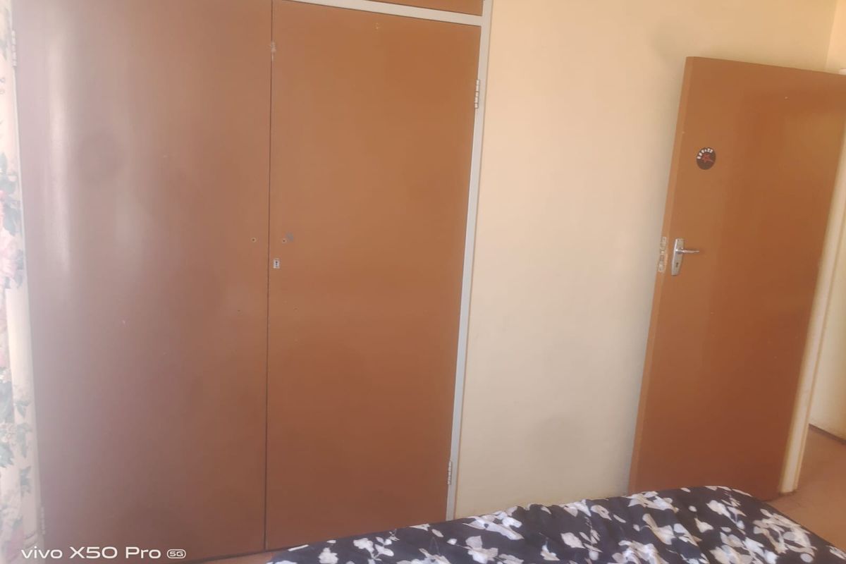 A bedroom featuring a built-in wardrobe and a standard internal door, offering functional storage space.