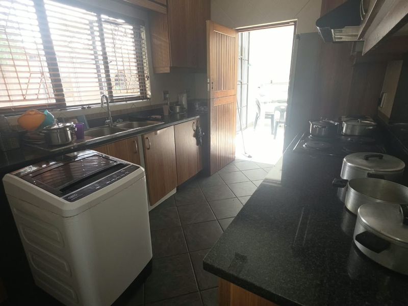 Functional kitchen featuring dark granite countertops, wooden cabinetry, built-in hob with extractor fan, and direct access to an outdoor area.