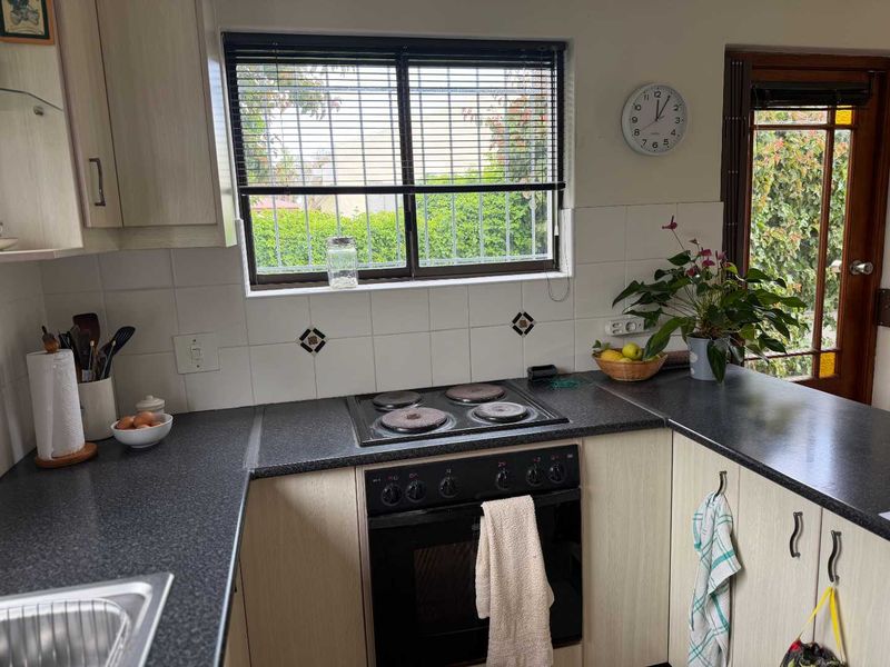 A functional kitchen featuring built-in cabinetry, dark laminate countertops, an electric hob, and an integrated oven with a tiled backsplash.