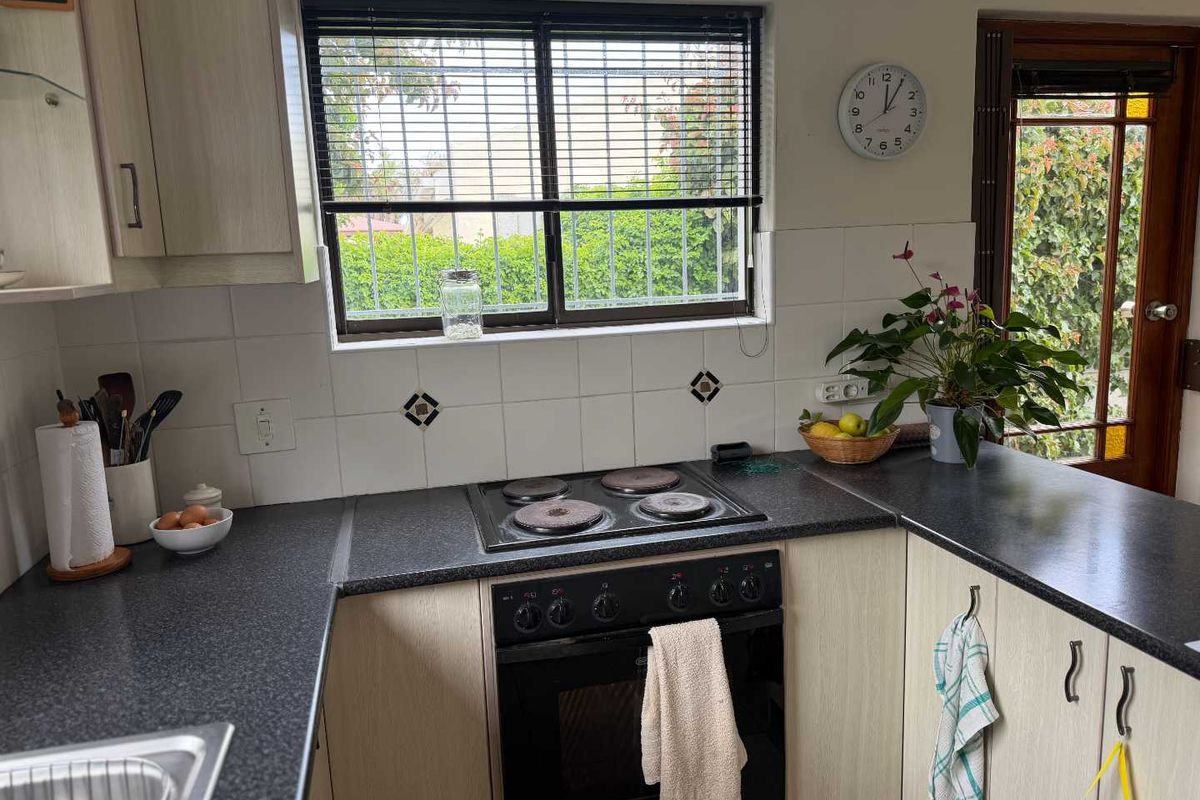 A functional kitchen featuring built-in cabinetry, dark laminate countertops, an electric hob, and an integrated oven with a tiled backsplash.