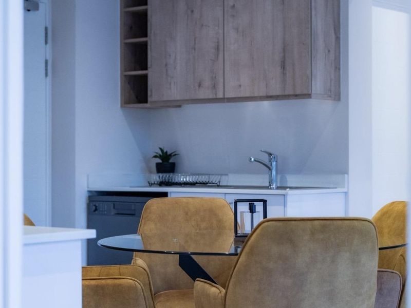 A compact kitchen area featuring modern wood-finish cabinetry, a clean countertop, and an integrated dishwasher, providing a functional and efficient workspace.